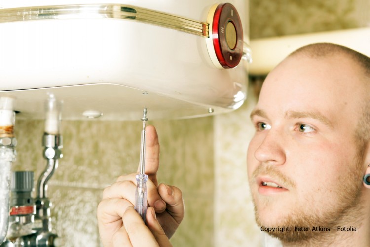 Ein Handwerker schraubt an einem Wasserboiler